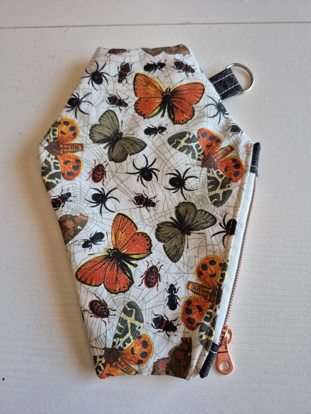 coffin pouch w/ spiders, moths, and Bettles, caught in a web in creme backing